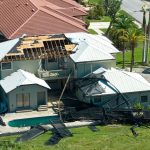 Home with severe roof damage and scattered debris after a hurricane