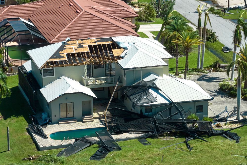 Home with severe roof damage and scattered debris after a hurricane