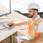 man in hi-vis vest inspecting roof